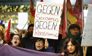 Women shout slogans and hold up a placard that reads "Against Sexism - Against Racism" as they march through the main railway station of Cologne, Germany, January 5, 2016. About 90 women have reported being robbed, threatened or sexually molested at the New Year's celebrations outside Cologne's cathedral by young, mostly drunk, men, police said on Tuesday.   REUTERS/Wolfgang Rattay - RTX215NV