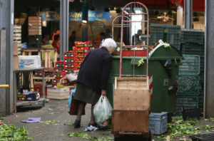 Poveri a Roma nel mercato rionale di Val Melaina raccolgono generi di prima necessità in terra tra gli scarti, un una foto d'archivio. Secondo l'Istat, un italiano su tre e' a rischio poverta', il 50% al sud. Roma, 16 dicembre 2013. ANSA/MASSIMO PERCOSSI / SIM