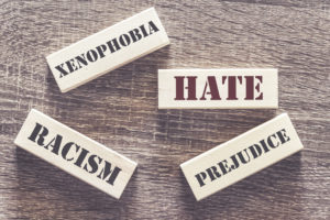 Hate, xenophobia, racism and prejudice words written with tiles on a wooden table